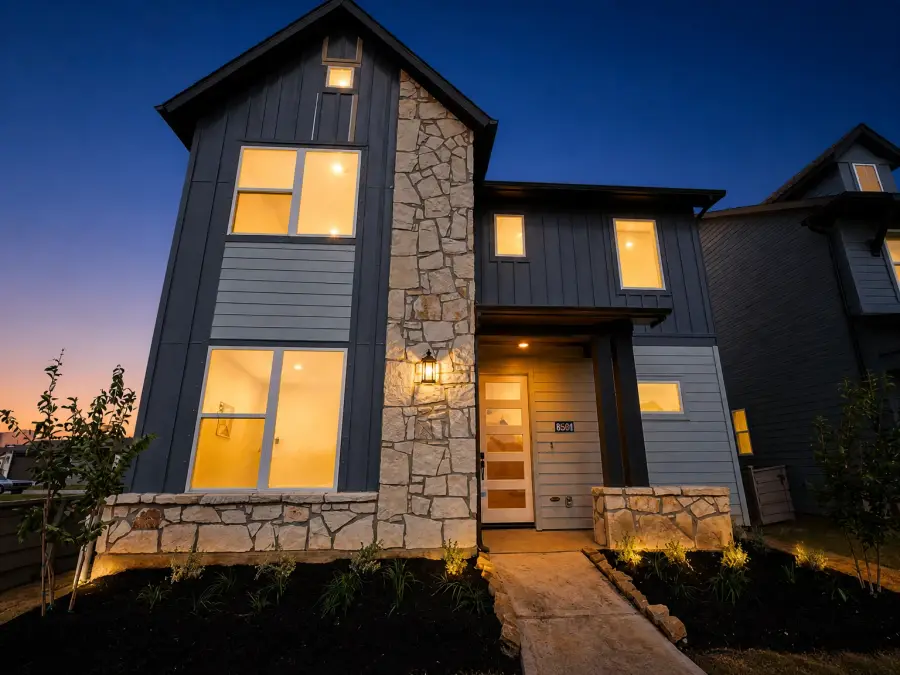 After AI day to dusk conversion, the same modern two-storey facade at blue hour with every window glowing, the porch lantern lit and the walkway edge-lit, structure identical