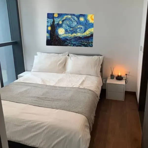 Apartment bedroom before AI restyling, with white bedding, a grey throw, a Starry Night print above the bed and a small white nightstand with a candle