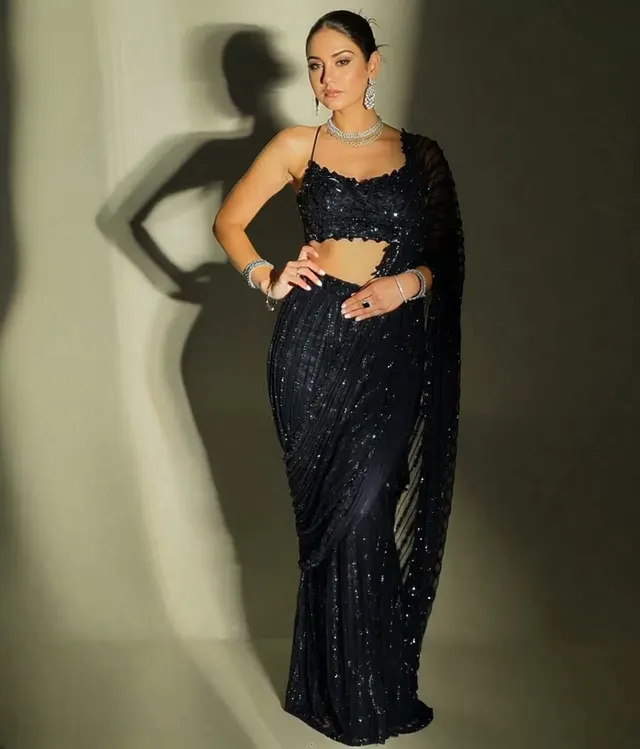 AI fashion video ad: a model in a black sequinned saree posing against a spotlit wall