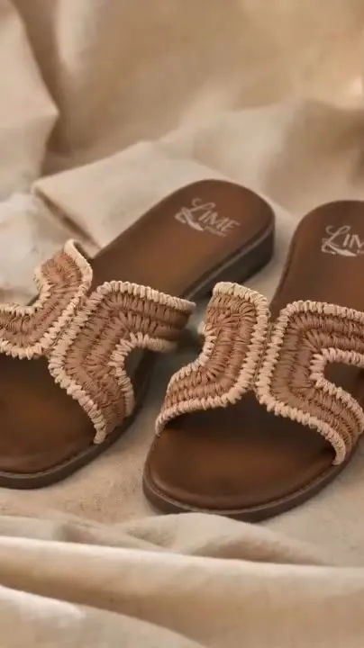 AI product video frame: a pair of woven raffia sandals resting on cream linen
